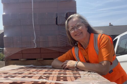 IMG_4250 Ruth leaning on a pack of bricks with other bricks stacked up behind her