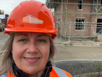 Photo of me onsite 1 Ruth in orange hard hat and hi vis jacket on a building site